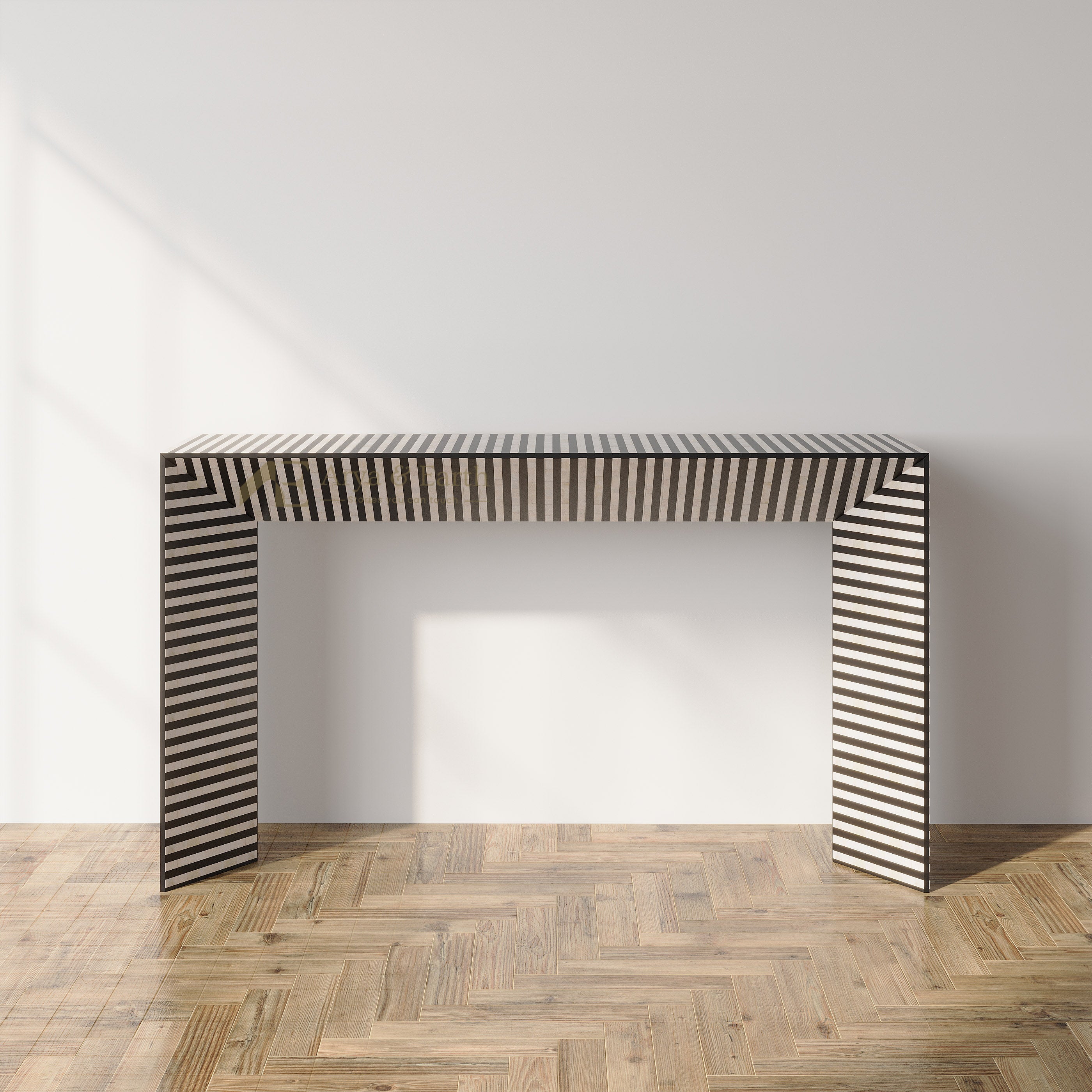 A modern console table with a black and white striped pattern, set against a minimalist white wall and light wood herringbone floor.