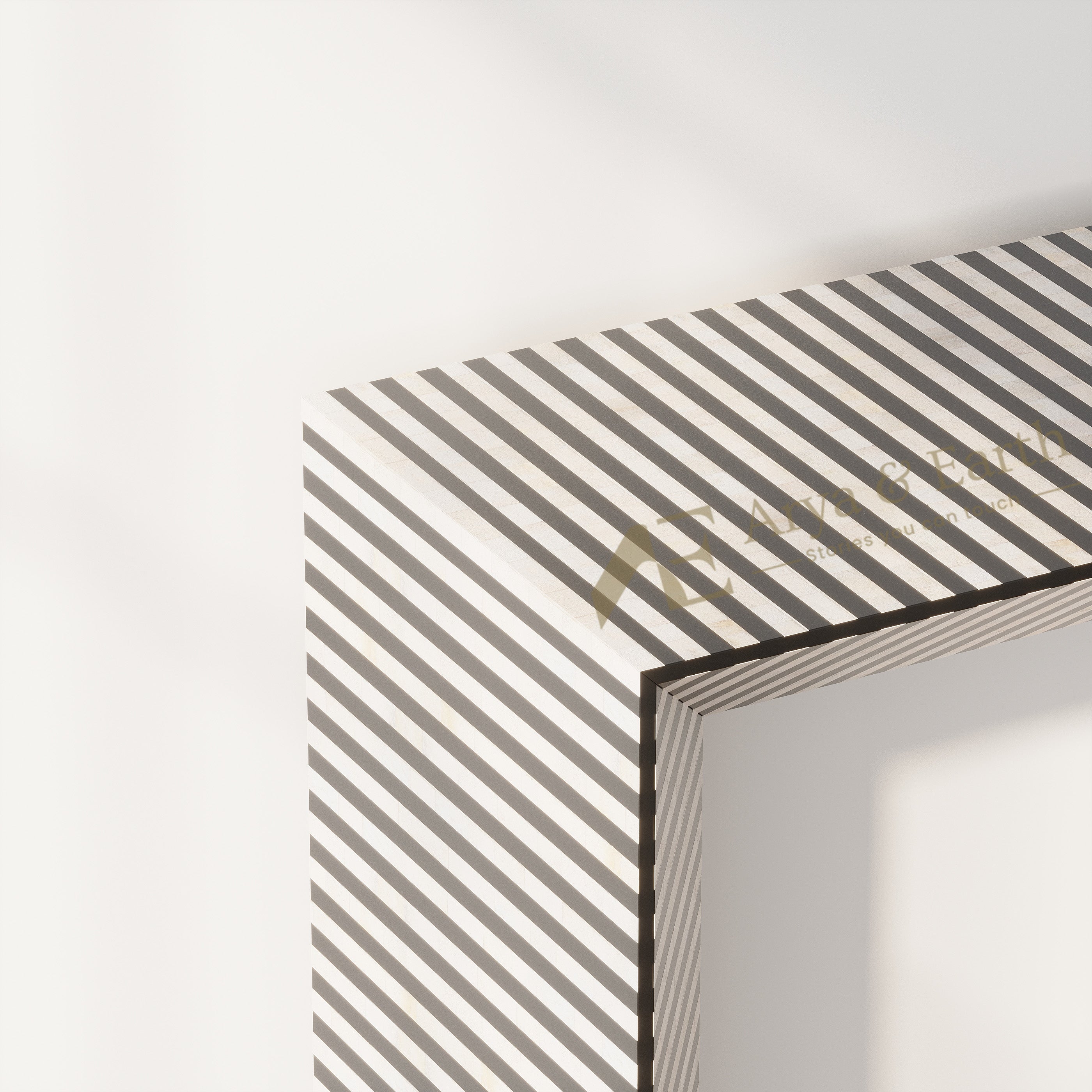 A close-up of a framed wall art piece showing a geometric corner with diagonal black and white stripes on the outer surface, photographed against a clean white wall.