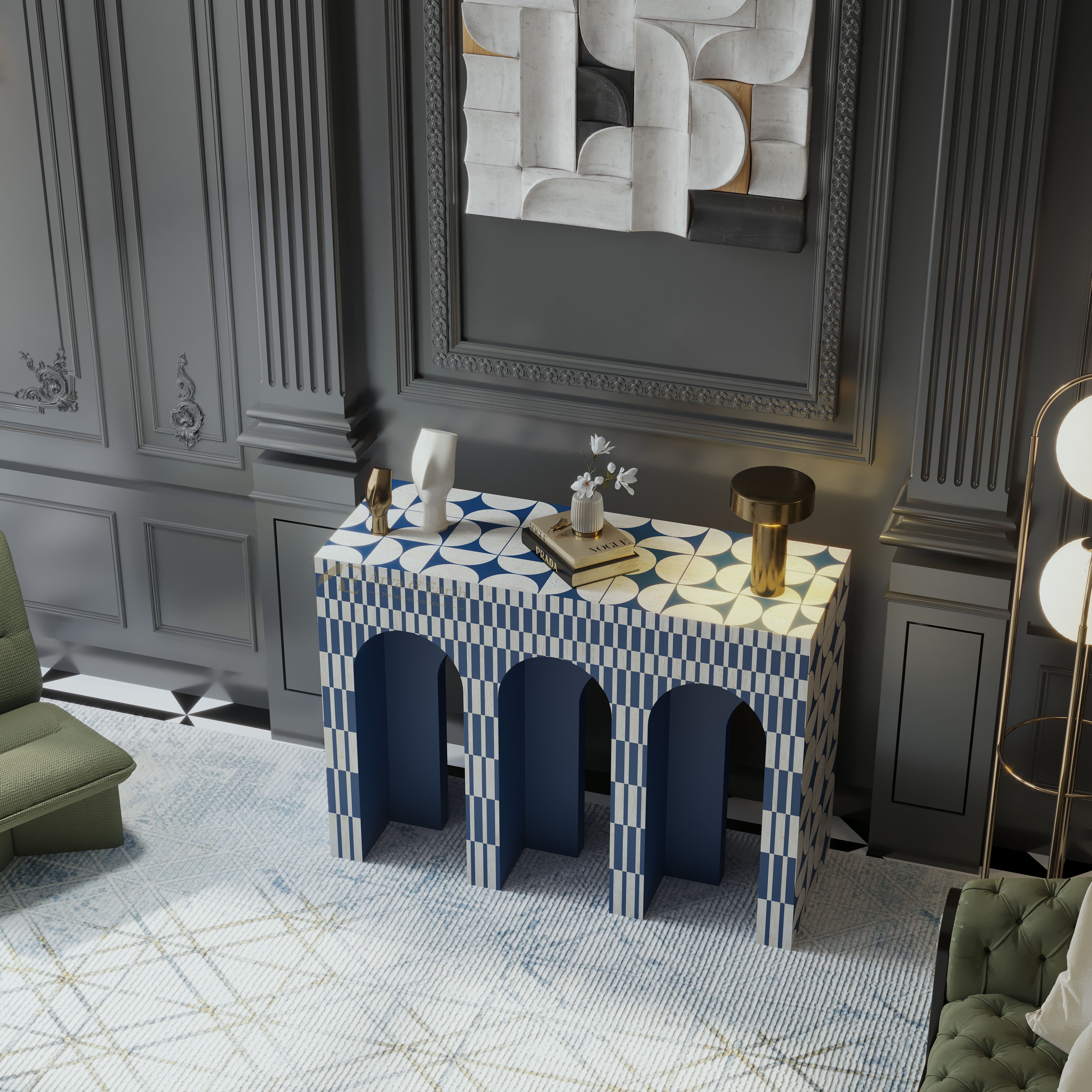 A decorative console table with a blue and white geometric patterned top and three arched legs, styled in a luxury room with gray paneled walls, a green armchair, and a gold floor lamp.