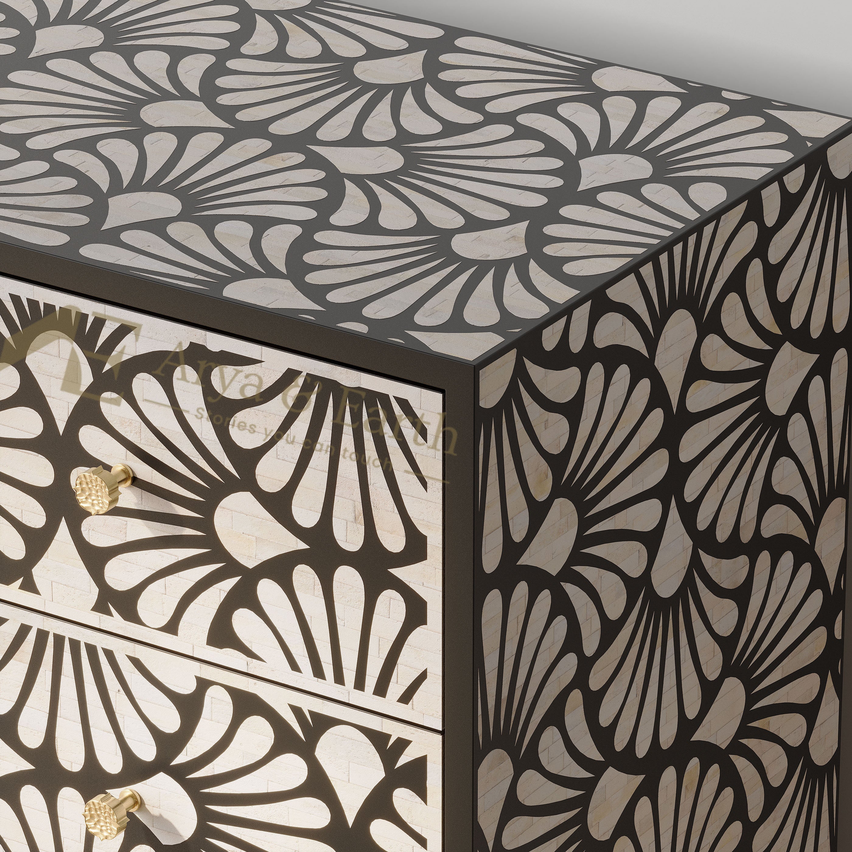 A close-up of a decorative sideboard or cabinet corner with a black frame and a repeating fan-shaped inlay pattern over cream and light beige panels. Two drawers are visible on the left with small gold-toned handles.