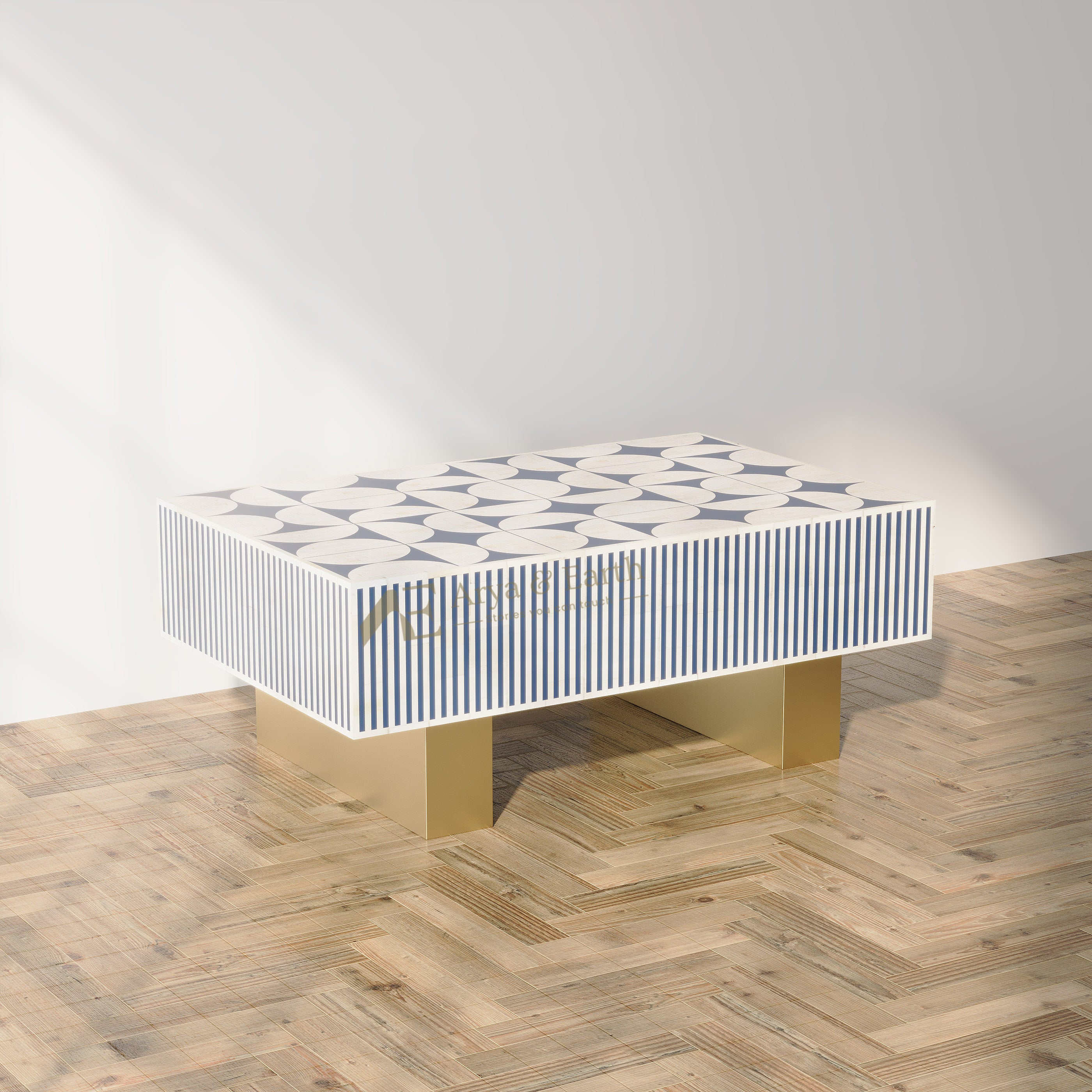 A modern rectangular coffee table with a white top featuring a navy blue geometric star pattern, flanked by vertical navy and white stripes on the sides, supported by two gold-colored block legs on a light wood herringbone floor.