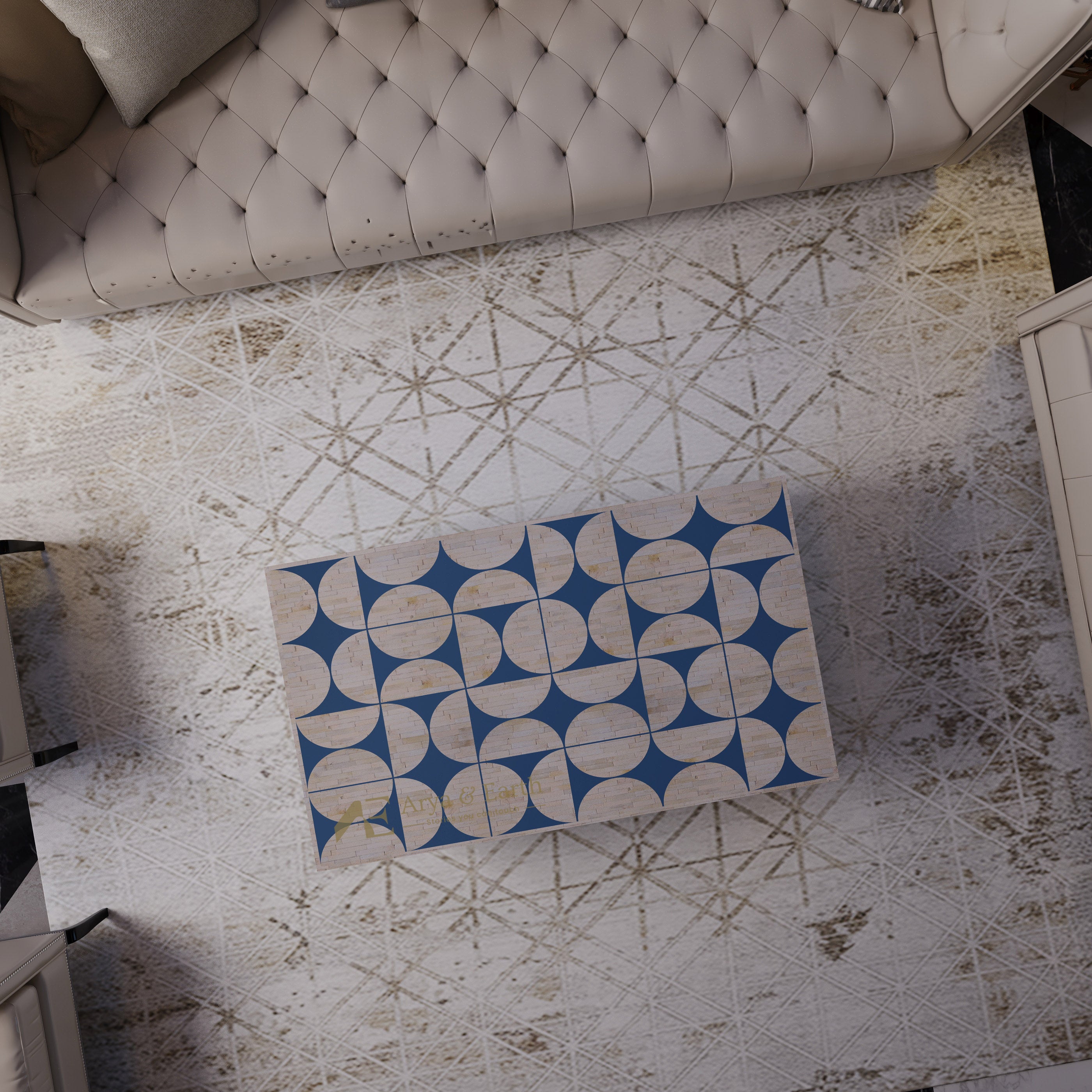 A rectangular ottoman or coffee table with a geometric pattern of blue and beige semicircles, shown from a top-down perspective on a distressed white patterned rug next to a tufted sofa.