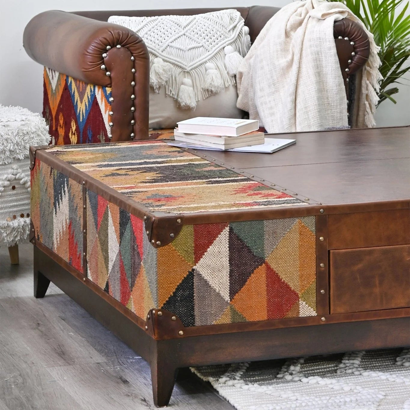 Wooden coffee table with geometric kilim pattern and leather accents in a home setting.
