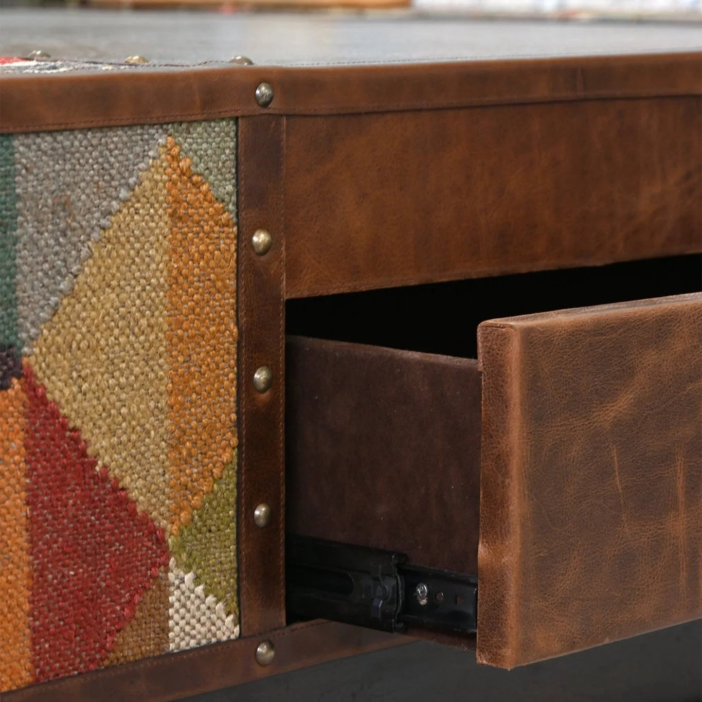 Close-up of a wooden drawer with geometric patterned side, blurred background