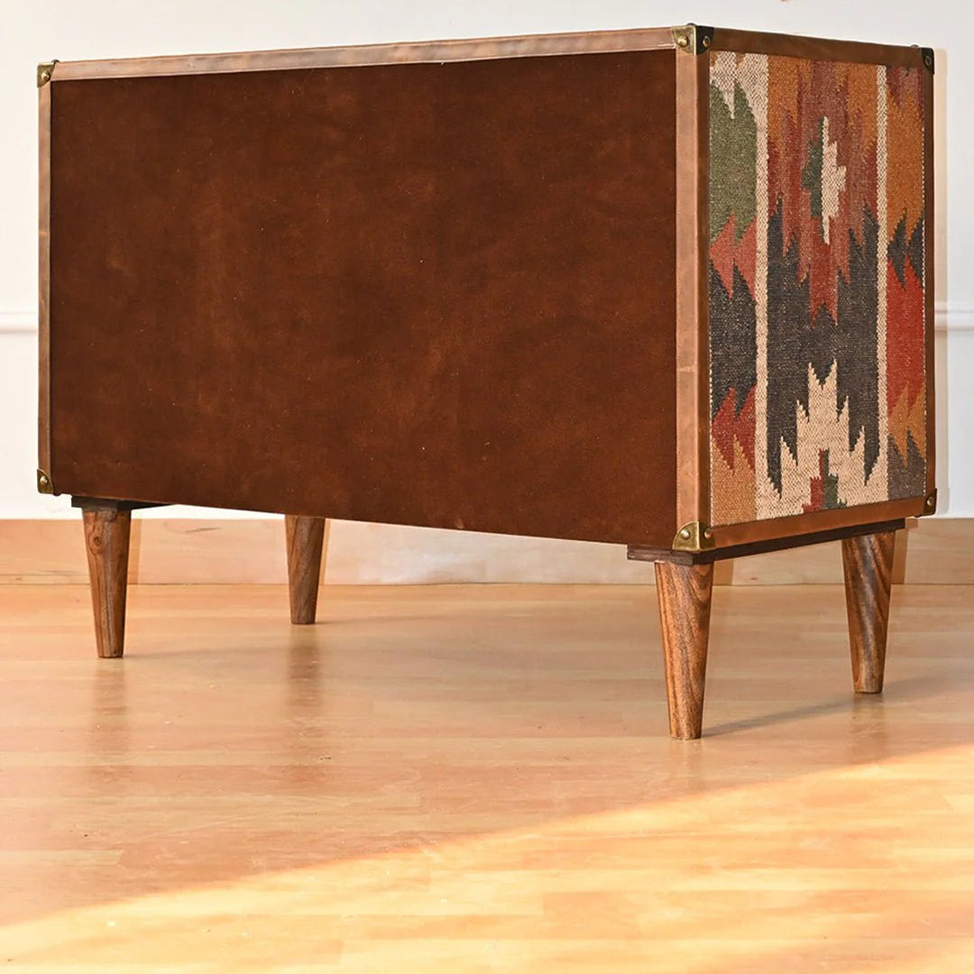 Wooden side table with leather and patterned fabric finish on a wooden floor.