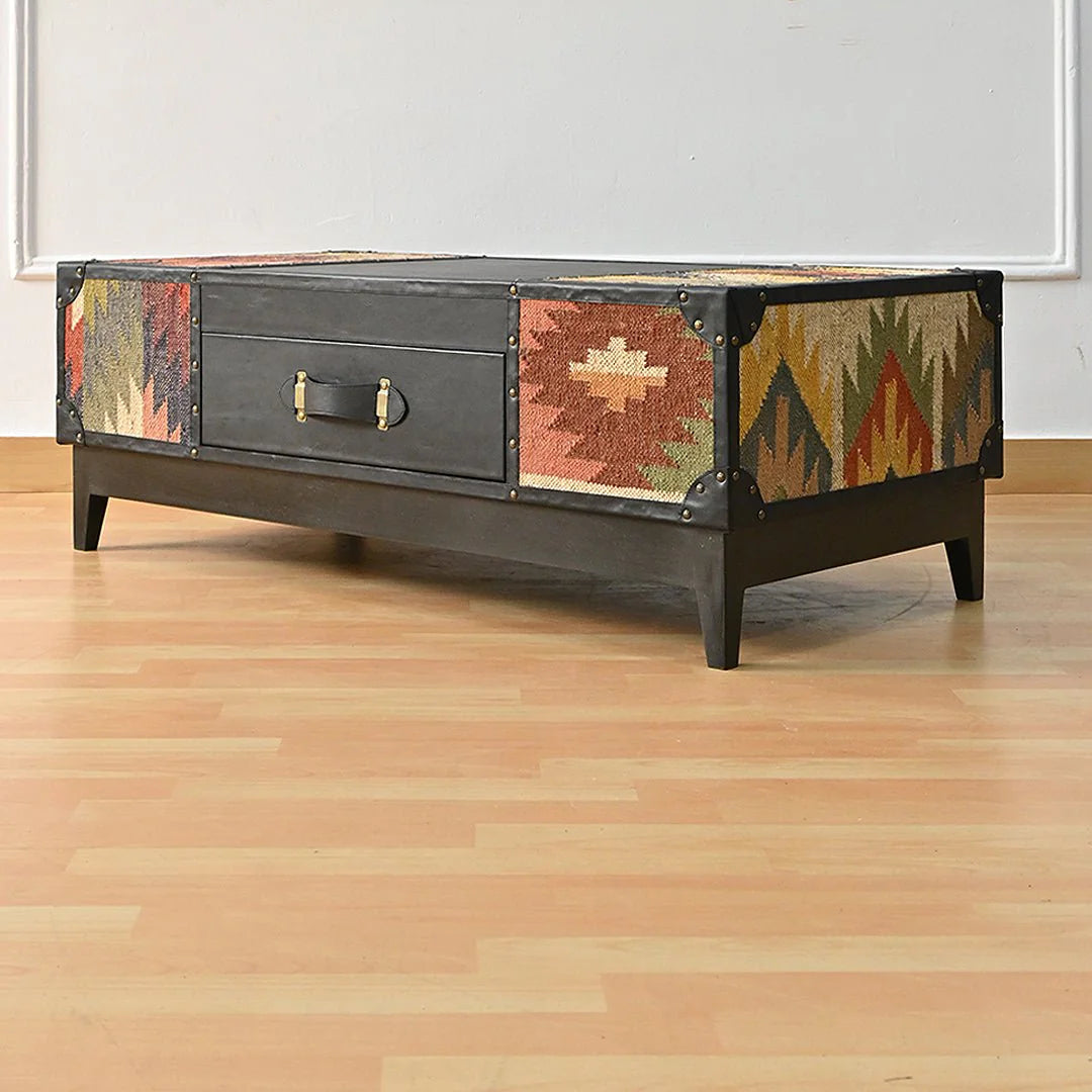 Decorative coffee table with geometric patterned sides on a wooden floor.