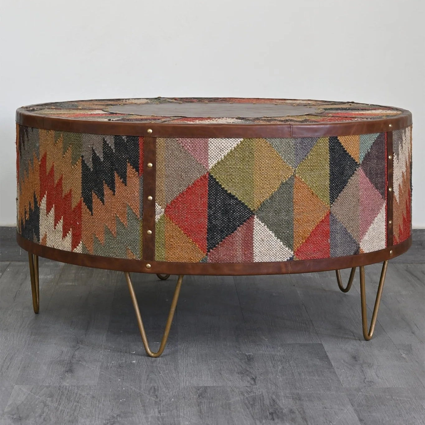 Round coffee table with geometric patterned top on a gray floor.