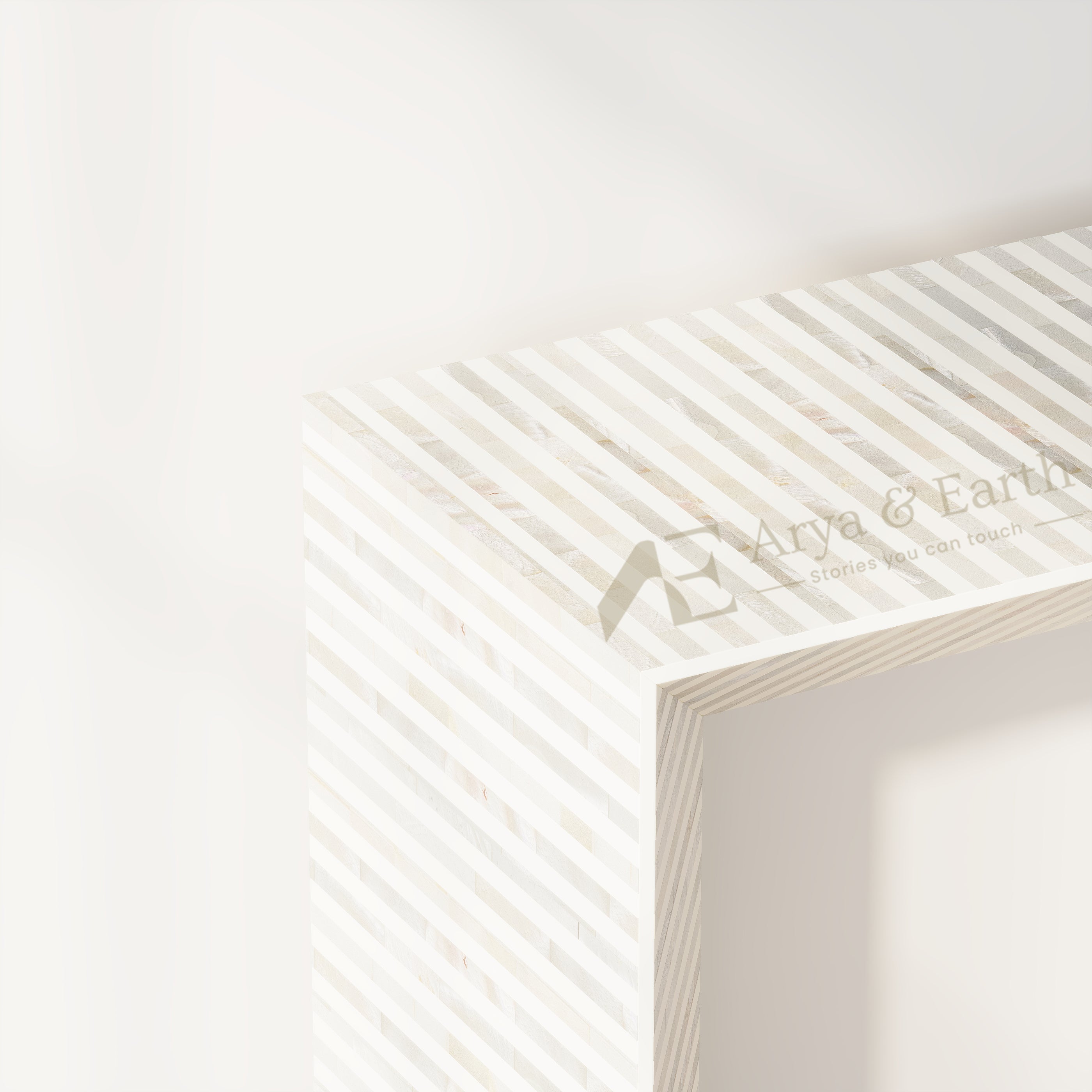 A close-up of a white floating shelf with a striped pattern of light wood and white mother-of-pearl inlays, featuring a watermark logo for 'Arya & Earth'.