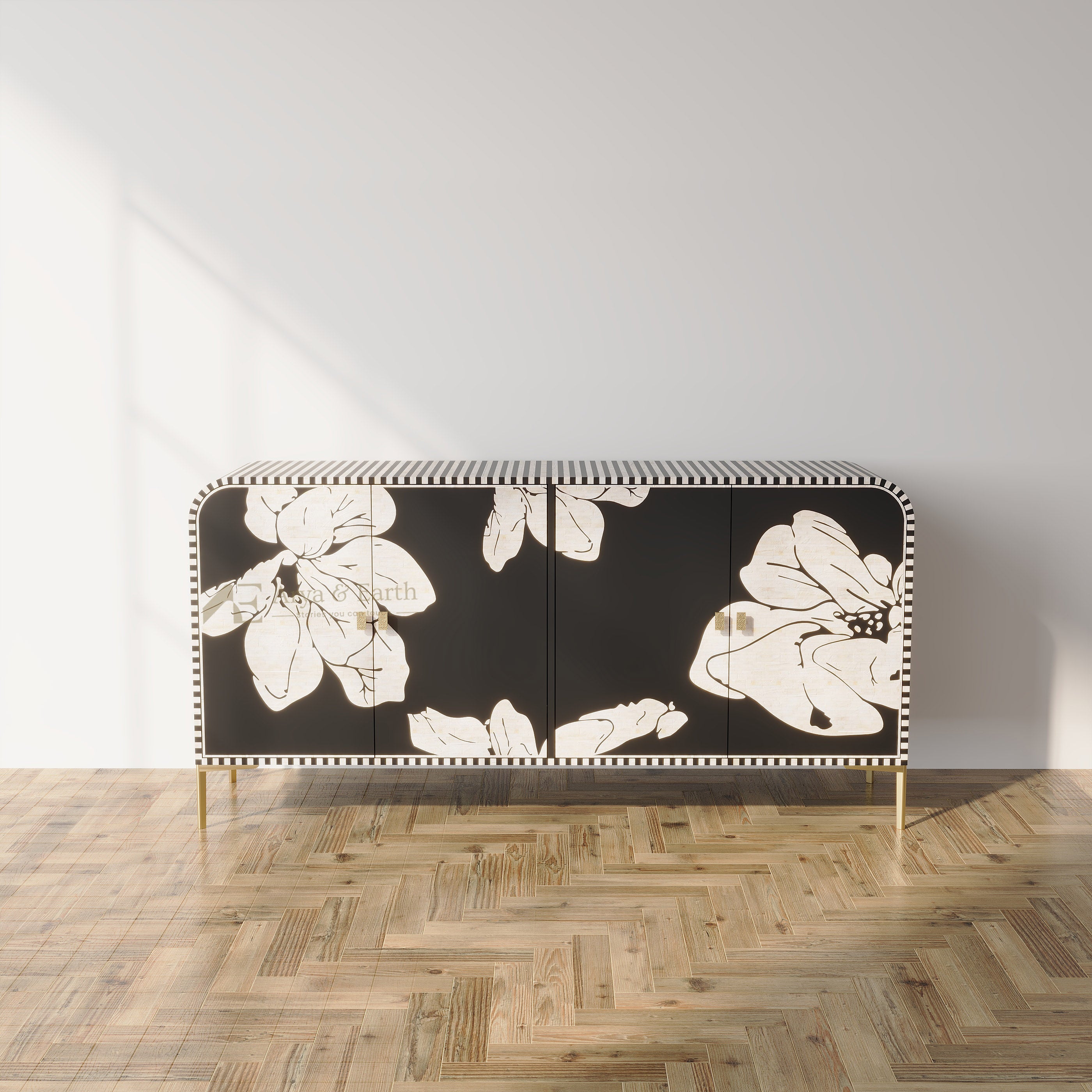 A modern sideboard cabinet with a black background and large white floral pattern, supported by slim gold legs, set against a minimalist white wall and light wood herringbone parquet floor.