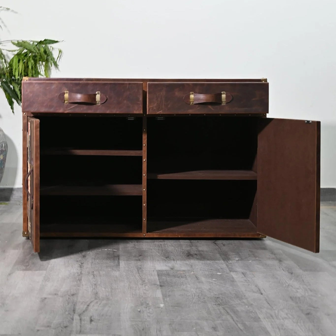 Dark wooden sideboard with open door on a gray floor against a white wall