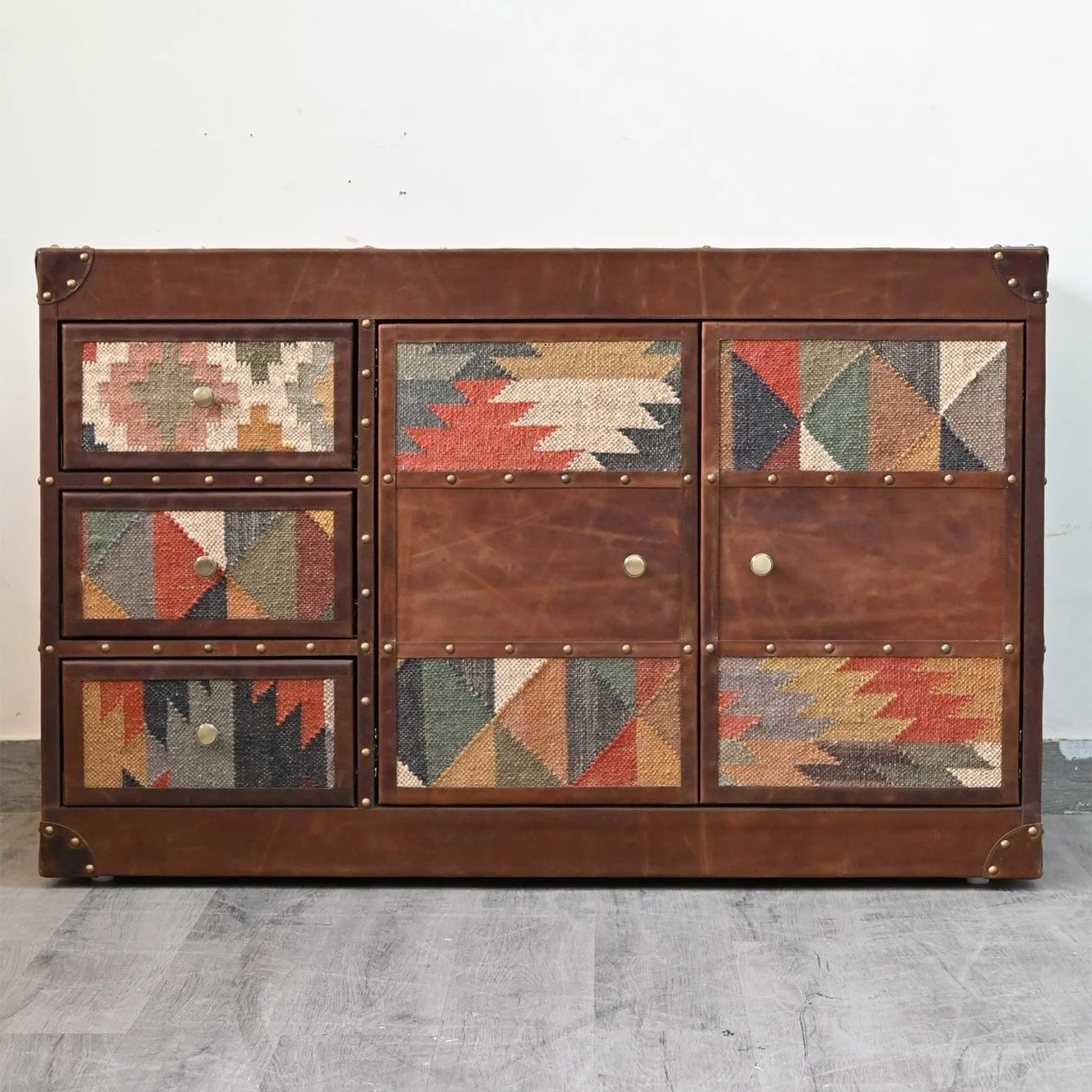 Wooden dresser with geometric patterned doors on a gray floor and white wall