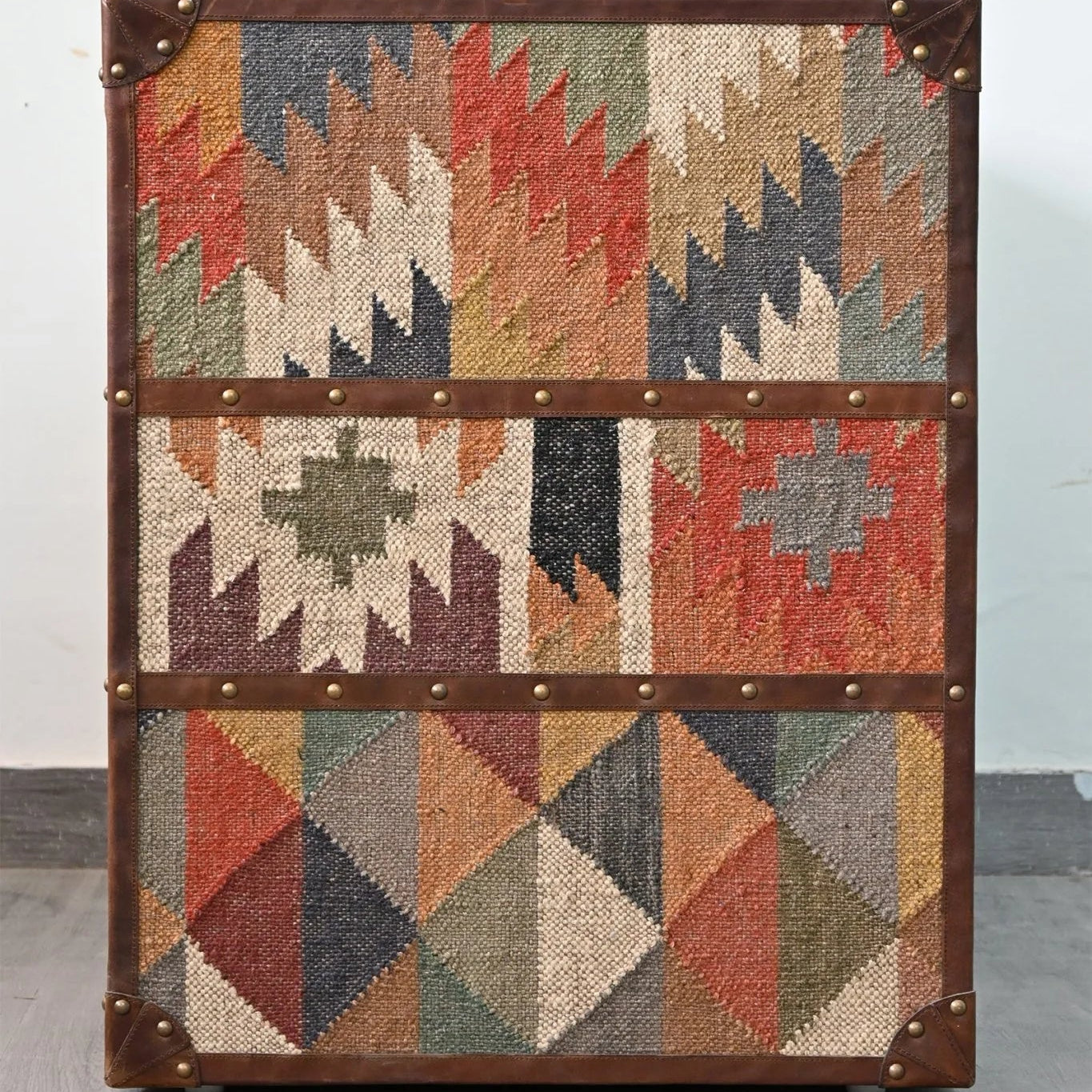 Vintage suitcase with geometric patterned fabric on a gray floor.
