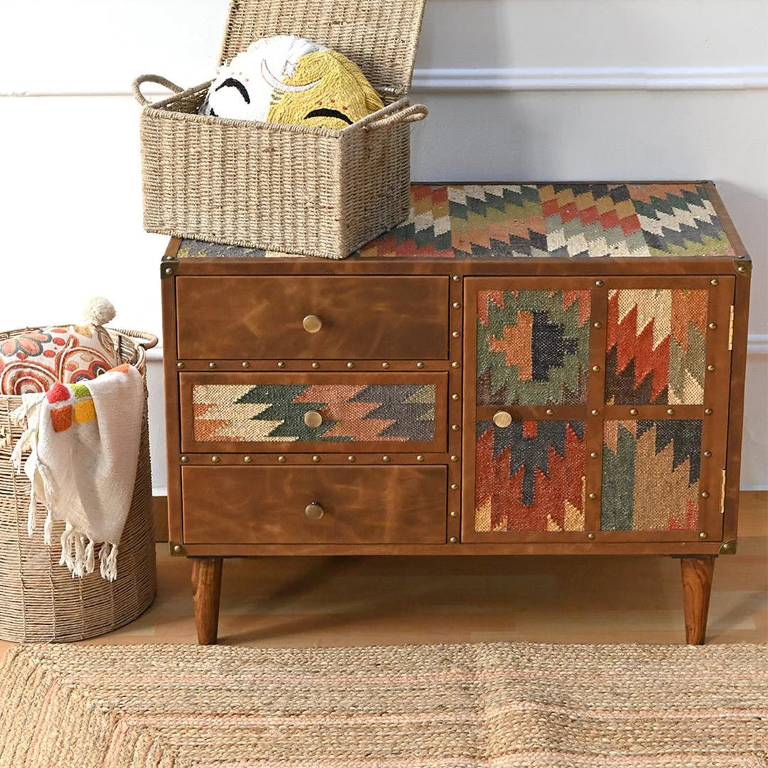 Wooden dresser with patterned doors and a woven basket on top, in a room setting.