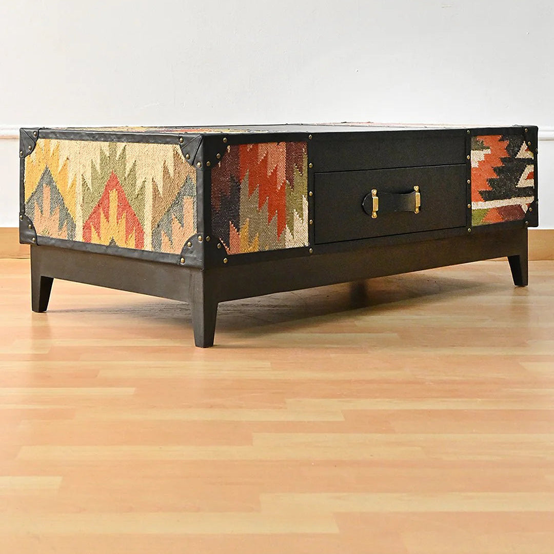 Wooden coffee table with patterned side panels on a wooden floor.