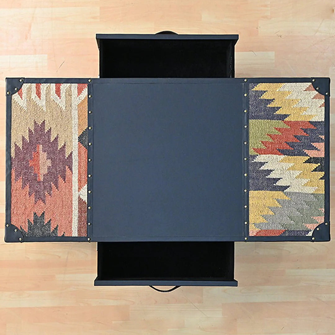 Black storage coffee table with patterned side panels on a wooden floor.