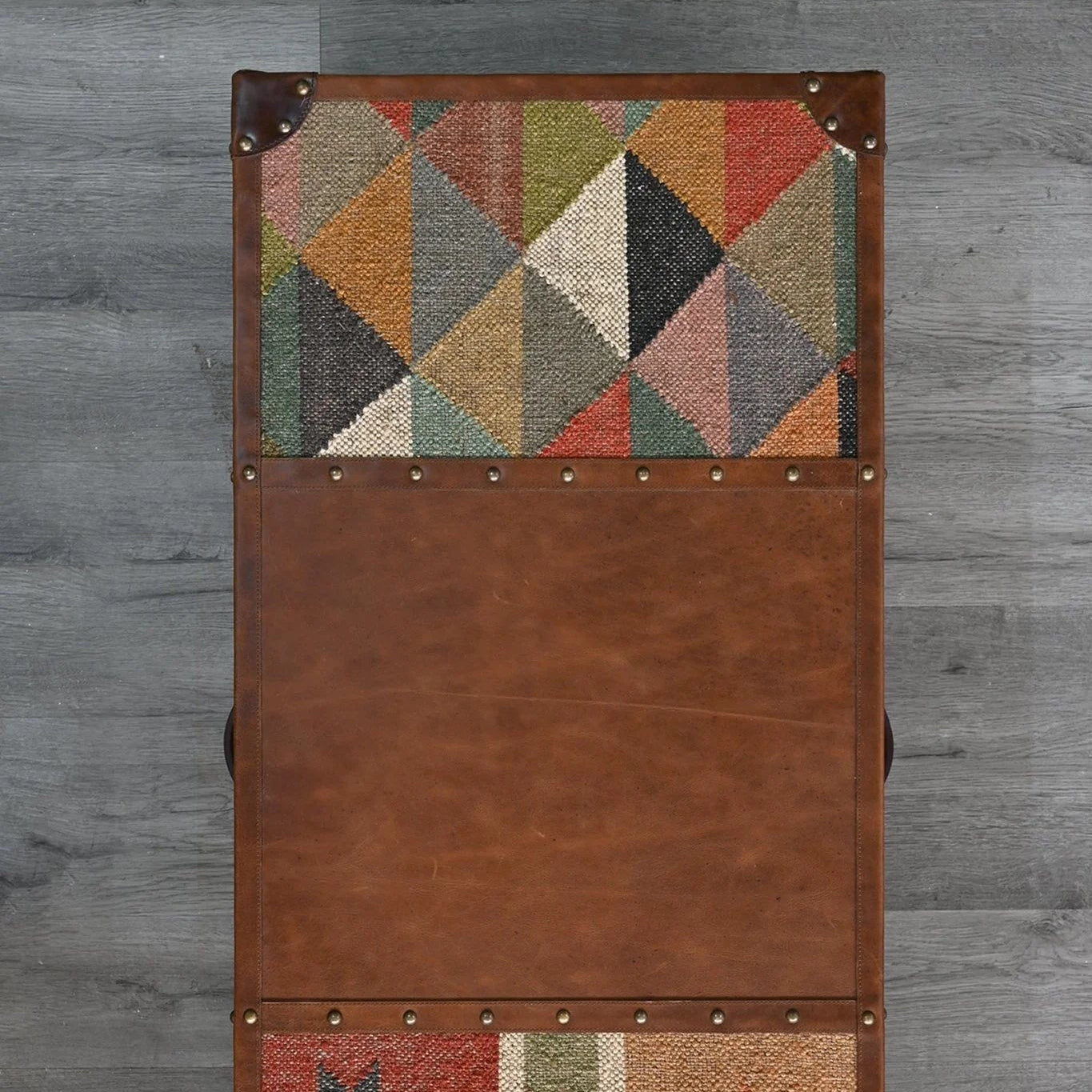 Brown leather cabinet with geometric patterned panels on a gray wooden background