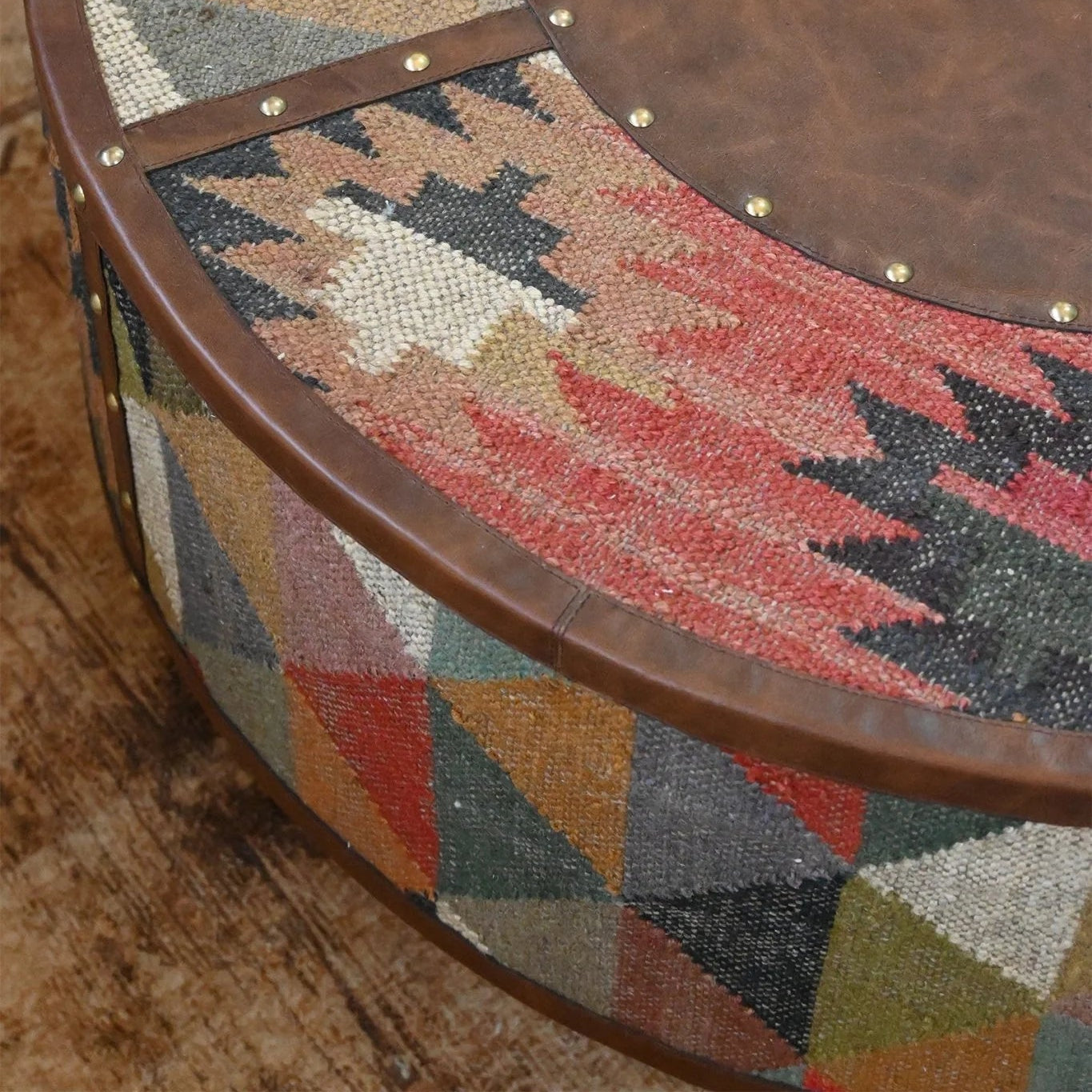 Round wooden table with a patterned fabric top on a wooden floor.
