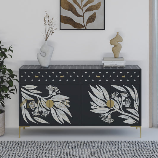 Black cabinet with floral and leaves pattern in a room with a plant and artwork on the wall.