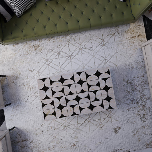 top view of Black and white patterned  bone inlay coffee table on a textured rug with a green upholstered sofa
